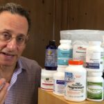 A person stands next to a variety of magnesium supplement bottles and containers displayed on a wooden surface.