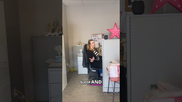 Person sitting at a desk in an office cubicle. A pink star decoration is on the cubicle wall. The word "SLEEP" is visible on the image.